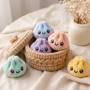 May include: A set of five small, plush, crocheted dumplings with embroidered smiling faces, rosy cheeks, and large black eyes. The dumplings are coloured light blue, purple, peach, mint green, and yellow, and are displayed with a tan crocheted basket.