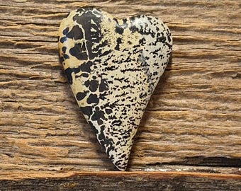 May include: A heart-shaped stone cabochon featuring a polished surface with a cream-colored base and intricate, branching black dendrite patterns that resemble organic, fern-like formations spread across the entire face of the stone.