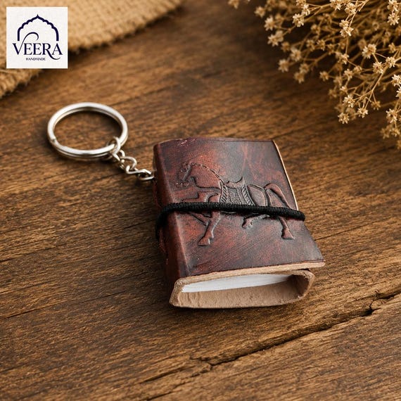 A genuinely tiny leather-bound notebook on a keychain — the kind of pocket-sized artifact a writer or traveler actually keeps forever.