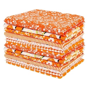 Op de afbeelding: Een stapel gevouwen stoffen vierkanten met diverse oranje en witte patronen. De ontwerpen bevatten bloemmotieven, dunne strepen, kleine geometrische vormen en stippen, allemaal uitgevoerd in een consistent oranje en wit kleurenpalet.