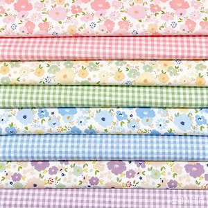 以下が含まれることがあります： ピンク、イエロー、グリーン、ブルー、パープルのパステルカラーのパレットで、花柄プリントとギンガムチェックが交互に並んだ、折りたたまれた生地のロールのコレクション。水平に積み重ねて配置されています。