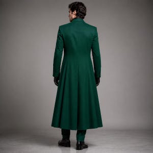 May include: A floor-length, dark green coat with long sleeves and a structured collar. The garment features a fitted bodice that transitions into a flared, pleated skirt section, extending down to the ankles. The coat is worn with black gloves.