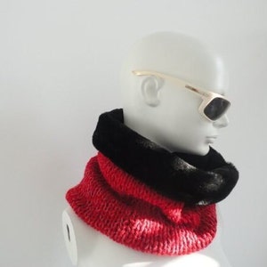 May include: A red and black knitted neck warmer with a faux fur lining. The neck warmer is being worn by a mannequin wearing gold-rimmed sunglasses.
