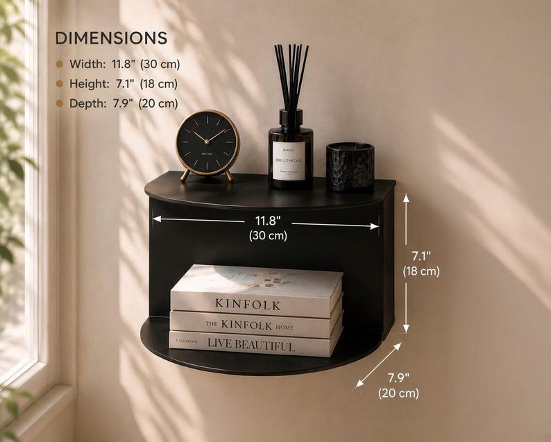 May include: A black semi-circular wall shelf with a flat top and curved front. Dimensions are 11.8 inches wide, 7.1 inches high, and 7.9 inches deep. The shelf holds a round clock, a reed diffuser, a candle, and three stacked books.