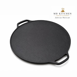 May include: A round black cast iron griddle with two integrated side handles. The surface is flat and circular. In the upper right corner, the text reads MB KITCHEN PREMIUM KITCHENWARE Built to last. Made to cook. with a small dome icon above.