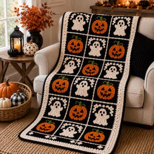 May include: A rectangular crochet blanket featuring a grid pattern of alternating black squares with white ghost motifs and orange jack-o'-lantern motifs. The blanket is bordered by a cream-colored crocheted edge and has a repeating Halloween theme.