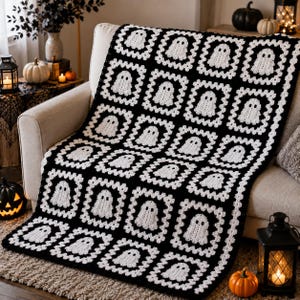 May include: A crochet blanket featuring a repeating pattern of white ghost motifs centered within black square frames. The textile is constructed from individual granny squares joined together, creating a grid of white ghosts on a black background.