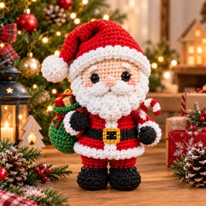 Könnte beinhalten: Eine gehäkelte Weihnachtsmann-Figur in einem roten Anzug mit weißem Besatz, einem schwarzen Gürtel mit gelber Schnalle und schwarzen Stiefeln. Die Figur hält einen grünen Sack mit einem kleinen Geschenk und eine rot-weiß gestreifte Zuckerstange.
