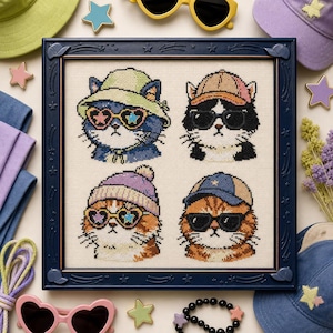 May include: A framed cross-stitch embroidery featuring four cats wearing hats and sunglasses. The top left cat wears a green bucket hat and heart-shaped glasses. The top right cat wears a baseball cap and black sunglasses. The bottom left cat wears a purple beanie and heart-shaped glasses. The bottom right cat wears a blue baseball cap and black sunglasses.
