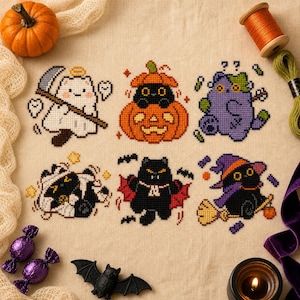 May include: A cross-stitch pattern on beige fabric featuring six Halloween-themed cats: a ghost with a scythe, a cat in a pumpkin, a purple cat, a mummy cat, a vampire cat with wings, and a witch cat on a broomstick, surrounded by craft supplies.
