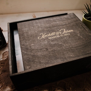 May include: A dark wooden box with a hinged lid. The lid is engraved with the text "Hochilt & Jason March 31, 2012".