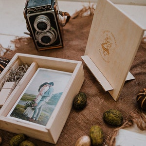 May include: A wooden photo box with a printed photo, a wooden USB drive, and a wooden photo stand. The photo shows a couple embracing. A vintage camera and decorative items are also present.