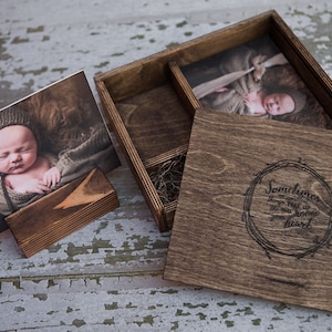 May include: A wooden box with a hinged lid, containing two photographs. The lid has a quote engraved on it: "Sometimes things fall in to place, and sometimes you have to move them with your own heart".