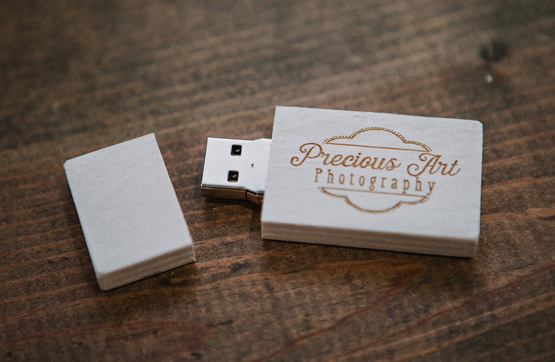 Puede incluir: Unidad USB de madera blanca con un logotipo grabado en oro que dice "Precious Art Photography".
