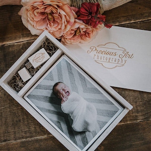 May include: A wooden box set for photography, containing a photo print of a baby, a USB drive, and a small box. The box is open, revealing the contents. The words "Precious Art Photography" are printed on the box and USB drive.
