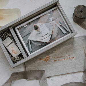 May include: A gray wooden box with a photo of a table setting inside. The box also contains a wooden USB drive with a bird design and the text "The Kids Are Alright".