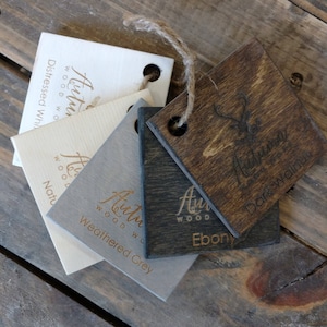 May include: Wood stain samples in distressed white, natural, weathered grey, ebony, and dark walnut. Each sample is labeled with the name of the stain and the Autumn Wood logo.