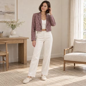 May include: A mauve cropped blazer with a subtle floral pattern, featuring a single button closure and notched lapels, paired with a white cropped tank top and high-waisted white trousers, completed with light-colored slip-on shoes.