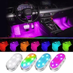 May include: A set of four oval-shaped LED interior car lights with clear plastic casings. Each light features multiple small bulbs capable of emitting various colors, including white, green, blue, and pink, as shown in the car interior display.