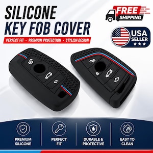 May include: Two black silicone key fob covers featuring a honeycomb texture on the sides and a thin blue, white, and red stripe detail. The covers have molded button icons for locking, unlocking, and trunk release functions on the front surface.