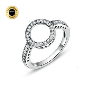 May include: A silver-toned ring featuring a circular centerpiece encrusted with small clear stones. The band is also adorned with a row of matching clear stones and features a series of small, dark, heart-shaped cutouts along the side profile.