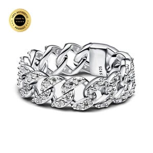May include: A silver-toned chain link ring featuring a series of clear, sparkling stones embedded along the front surface. The metal band is engraved with the text S925, indicating its composition. The design mimics a classic curb chain link style.