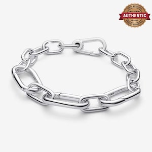 May include: A silver chain link bracelet featuring elongated, polished oval links connected in a continuous loop. The bracelet includes a secure, integrated carabiner-style clasp mechanism that matches the design of the other links.