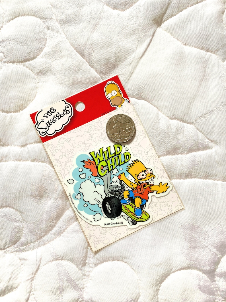May include: A yellow sticker featuring Bart Simpson riding a motorcycle with the words "Wild Child" in a yellow and green font. The sticker is on a white background with a red border and a small image of Bart Simpson in the top right corner.