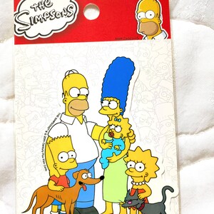 May include: A sticker sheet featuring the Simpsons family. The characters are Homer, Marge, Bart, Lisa, Maggie, Santa's Little Helper, and Snowball. The sticker sheet is white with a black outline and the text "The Simpsons" and "Matt Groening" in black.