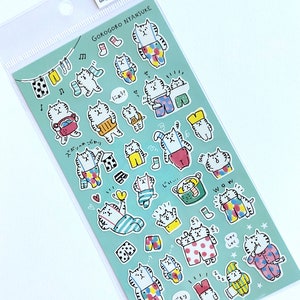 May include: A sheet of colorful stickers featuring illustrations of cats wearing different outfits and accessories. The stickers are on a light blue background and include Japanese text.