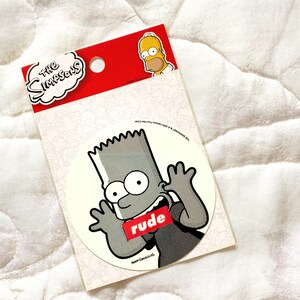 May include: A white sticker with a black and white image of Bart Simpson from The Simpsons cartoon. Bart is wearing a black shirt with the word "rude" printed in red on it. He is making a rude gesture with his hands. The sticker is on a white background.