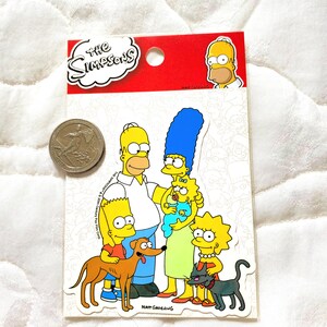 May include: A sticker sheet featuring the Simpsons family. The sticker sheet is red and white with the words "The Simpsons" in a white cloud. The sticker sheet includes Homer, Marge, Bart, Lisa, Maggie, Santa's Little Helper, and Snowball.