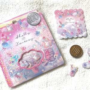 May include: A pack of 100 iridescent stickers featuring a unicorn, seashells, and other whimsical designs. The stickers are pink, blue, and white with glitter accents. The pack is labeled "Shelly Fantasy".