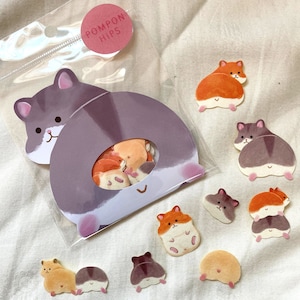 May include: A clear plastic bag with a sticker that says "Pompon Hips" and contains a variety of colorful hamster stickers. The stickers are in different poses, including sitting, standing, and running.