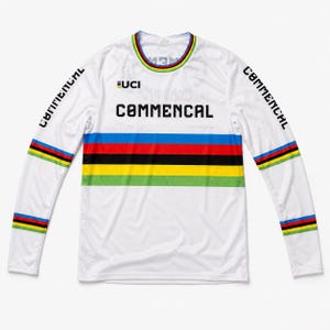 May include: A white long-sleeve jersey featuring the text COMMENCAL in black on the chest and sleeves. The garment includes a UCI logo and horizontal stripes in blue, red, black, yellow, and green across the chest, cuffs, and collar.