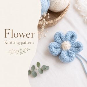 May include: A crochet flower with five light blue petals and a cream-coloured centre. The text "Flower Knitting pattern" is printed on the left side, accompanied by a small decorative branch illustration and a basket of yarn balls.