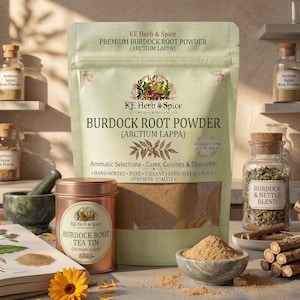 May include: A light green pouch of KE Herb & Spice Premium Burdock Root Powder, a copper-colored tea tin, a small stone bowl filled with brown powder, a botanical book, and a bundle of woody roots, all arranged with glass jars of herbs.