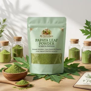 以下が含まれることがあります： 透明な窓が付いたKE Herb & Spiceパパイヤリーフパウダーのライトグリーンのスタンドパウチ。緑色のパウダーが入った4つのガラス瓶、パウダー入りの木製ボウル、木製スプーン、パパイヤの葉の植物画に囲まれています。