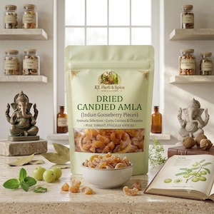 Könnte beinhalten: Ein hellgrüner Beutel mit KE Herb & Spice Dried Candied Amla Indian Gooseberry Pieces mit einem Sichtfenster, das bernsteinfarbene Früchte zeigt. Eine kleine weiße Schale enthält die kandierten Stücke, neben grünen Stachelbeeren und einem Buch.