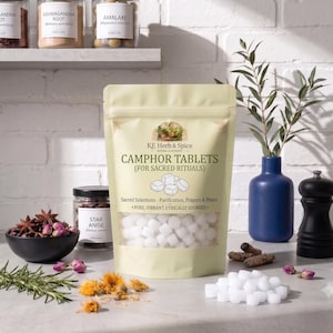 Puede incluir: Una bolsa vertical de color amarillo claro que contiene tabletas de alcanfor blancas. La etiqueta dice KE Herb & Spice, Camphor Tablets (For Sacred Rituals), Sacred Selections - Purification, Prayers & Peace, Pure, Vibrant, Ethically Sourced, con un gráfico de cubos.