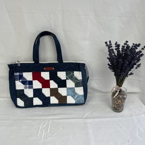 Peut inclure: Un sac fourre-tout rectangulaire en jean avec un panneau avant en patchwork composé d'un motif à carreaux blanc, rouge, bleu, marron et écossais. Le sac possède deux anses en jean bleu foncé, une fermeture éclair blanche et une étiquette.