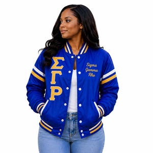 May include: A royal blue varsity jacket featuring gold Greek letters Sigma Gamma Rho on the right chest and the text Sigma Gamma Rho embroidered in gold on the left chest. The jacket has white and gold striped ribbed cuffs, collar, and hem.