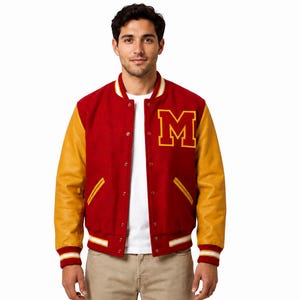 Może przedstawiać: Czerwona kurtka typu varsity z żółtymi skórzanymi rękawami, naszywką z żółtą literą M na piersi i białym t-shirtem pod spodem. Kurtka posiada zapięcie na zatrzaski, prążkowane mankiety w paski oraz dwie kieszenie po bokach.