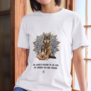 May include: A white t-shirt featuring a graphic of a person sitting cross-legged next to a wolf in front of a mandala design. Below the graphic, the text reads: "HER LOYALTY BELONGS TO NO ONE BUT HERSELF AND HER FUTURE" with a small circular logo below.