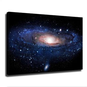 May include: A rectangular canvas wall art print featuring a vibrant spiral galaxy set against a deep black background. The galaxy displays a bright, glowing white and soft pink center, surrounded by swirling arms of dense blue and white starlight.