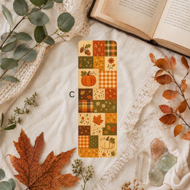 Fall bookmark with a patchwork pattern of pumpkins, acorns, maple leaves, flowers, plaid and botanical designs in orange, green, brown and yellow.