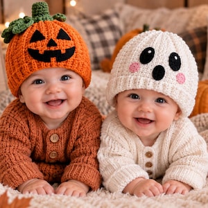 May include: Two crochet baby sweaters and matching hats. One set is orange with a pumpkin face design on the hat, and the other is white with a ghost face design on the hat. Both sweaters feature three buttons down the front center.