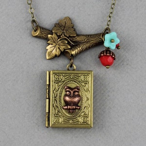 Puede incluir: Un collar dorado con un medallón que presenta un búho y una rama con hojas y cuentas. Las cuentas son rojas, azules y turquesas.