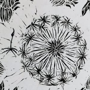 Pu&ograve; includere: Una stampa in linoleum in bianco e nero raffigurante un capolino di tarassaco centrale con sottili linee radianti e piccoli fiori a forma di stella. Il design include semi sparsi e elementi floreali parziali su uno sfondo bianco.