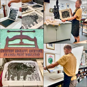 May include: A collage showing a printmaking process at Swansea Print Workshop. It features a black ink linocut print of a bull on paper, a metal printing press, and a person in a yellow shirt and black apron working with the equipment.